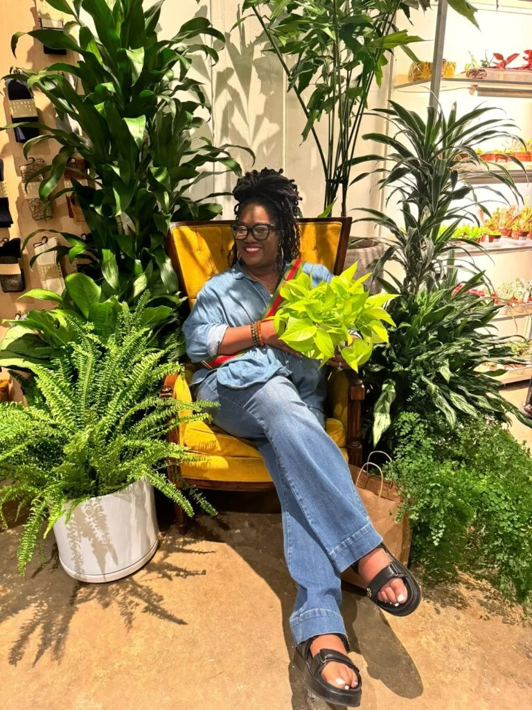 a woman sitting in a chair with plants